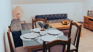 A cozy dining area with a table set for four, a sofa, a lamp, and a speaker. - Hvar spa & Apartments-superior 1 Bedroom Apartment (Jelsa)