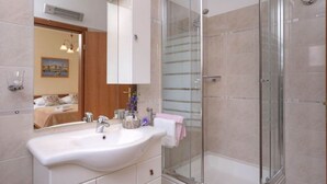 Un bagno moderno con doccia vetrata, lavandino bianco e uno specchio grande.