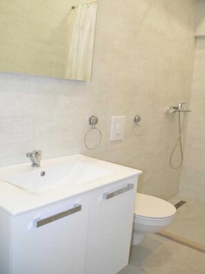 Ein Badezimmer mit einem weißen Waschbecken, einer Toilette und einer Dusche.