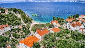 Ein Küstendorf mit terrassenförmig angelegten Häusern, einem Strand und freiem Blick auf das Meer.