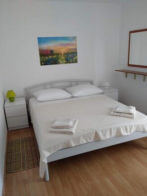 A single-bed room with a white bed, a nightstand with a lamp, a painting on the wall, and a wooden floor. - Apartments Blaza - Duplex Two Bedroom Apartment (Vodice)