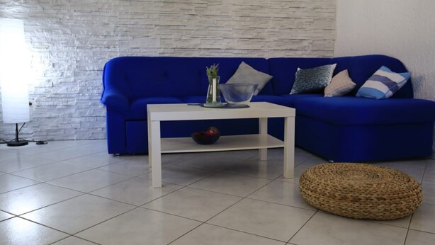 A living room with a blue sofa, a white coffee table, and a woven pouf. - Apartment Barbara - Two Bedroom Apartment With Terrace (Vir)