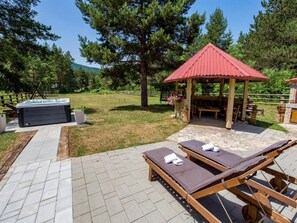 Ein Patio-Bereich mit Whirlpool, Liegestühlen und einem Pavillon.