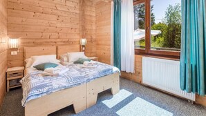 A wooden cabin bedroom with a bed, two bedside tables, a hanging light fixture, and a window with curtains. - Apartments Plitvice Forest - Superior One Bedroom Apartment With Terrace (Plitvicka Jezera)