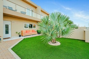 A modern two-story building with a well-maintained lawn and a single palm tree. - Luxury 3BR Pool Villa • 3 Baths • Villa Twin B (Noord)