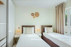 Une chambre d’hôtel avec deux lits, un élément décoratif fixé au mur et une fenêtre avec des rideaux.
