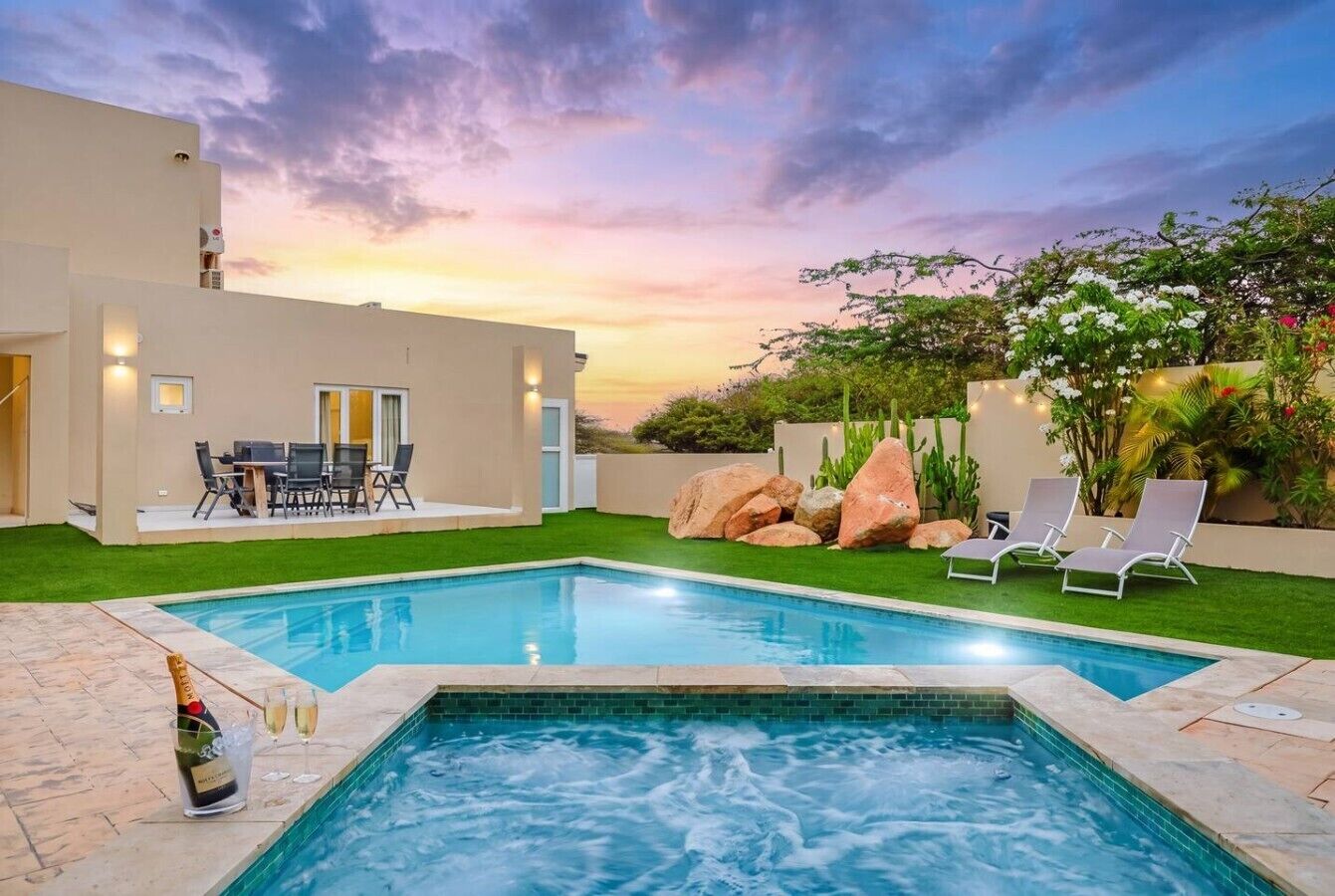 Une piscine avec un jacuzzi, un espace salon extérieur et une vue sur le coucher de soleil.