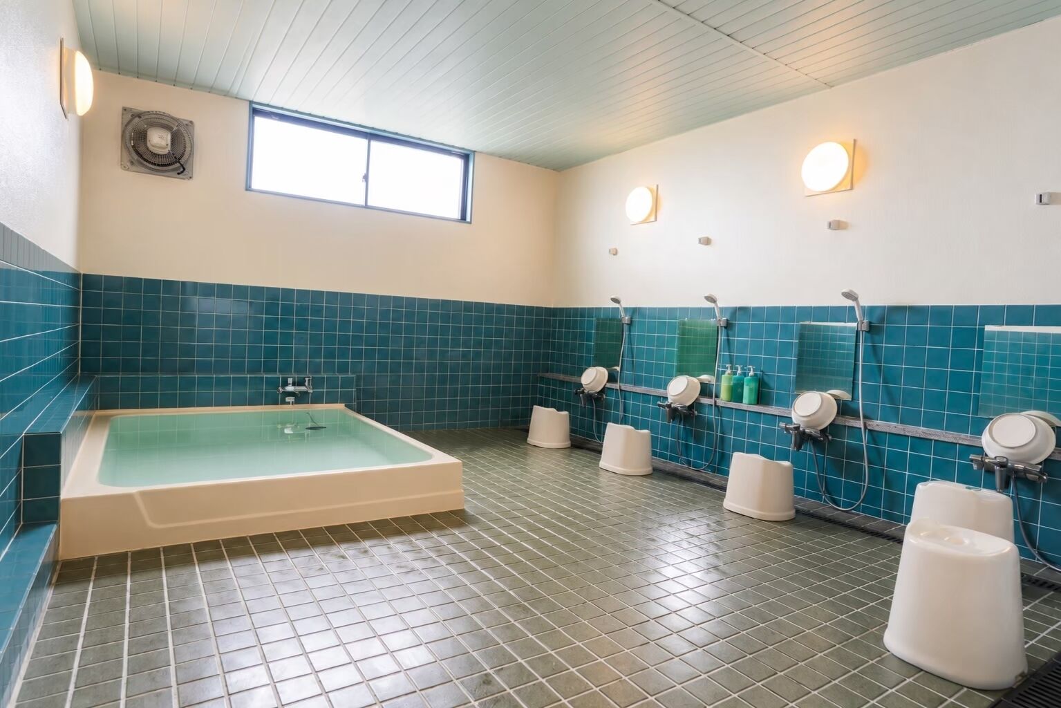 A bathroom with a large bathtub, multiple showerheads, and a tiled floor.