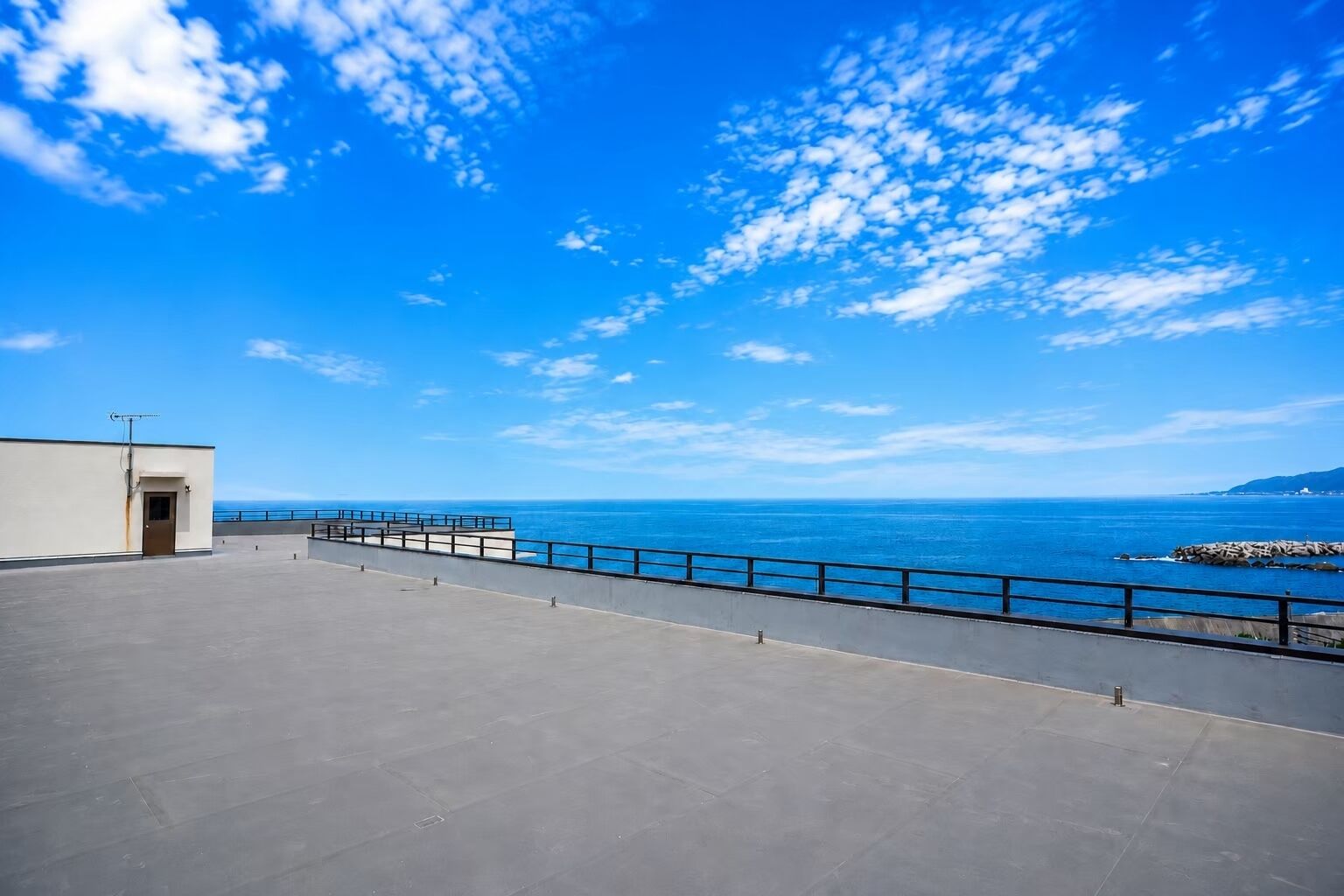 A rooftop terrace with a clear view of the ocean and a distant coastline.