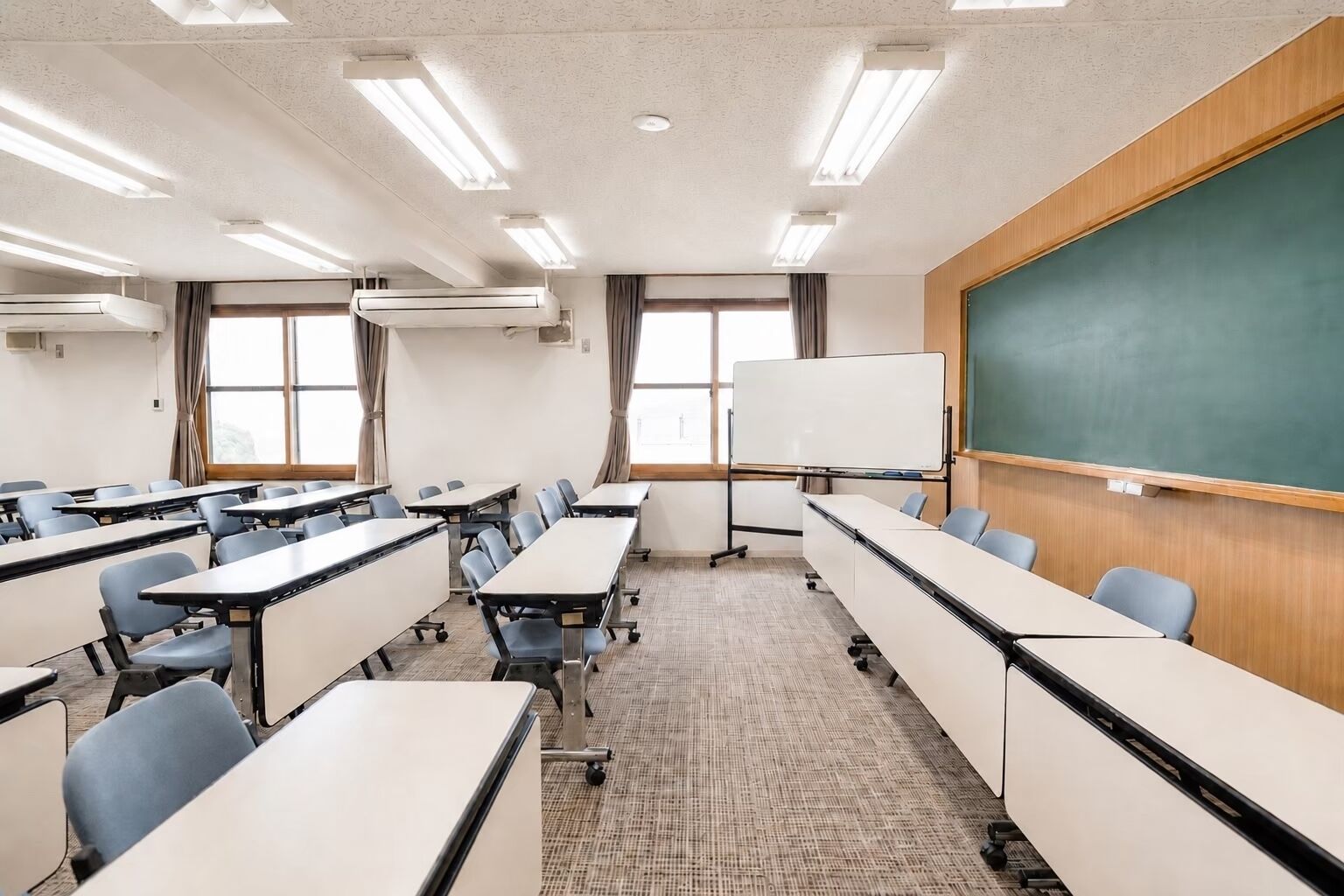 A classroom with desks, chairs, a whiteboard, and a chalkboard.