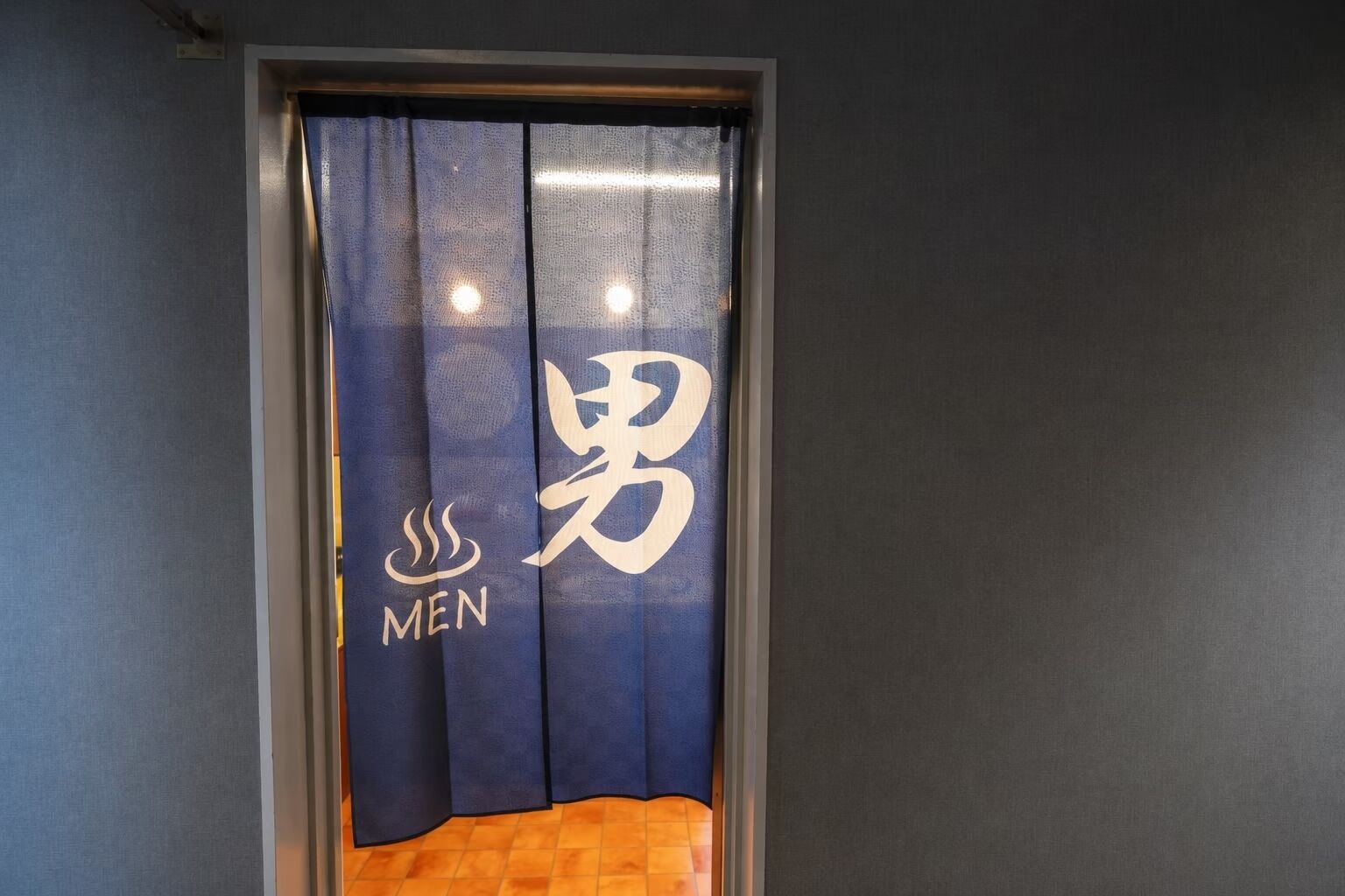A room with a dark blue curtain featuring a logo and the word 'MEN' on it.