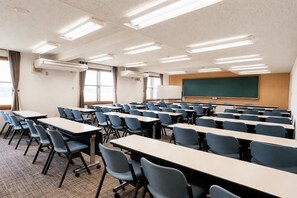 Un aula con filas de escritorios y sillas, una pizarra y una pantalla para proyector.