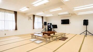 A room with tatami mats, a wooden table, a TV, and speakers.