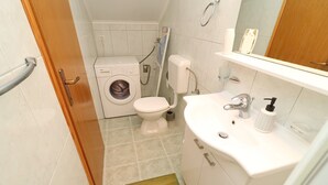 Ein kleines Badezimmer mit Waschmaschine, Toilette und Waschbecken.