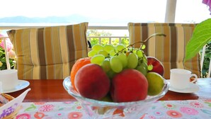 A table with a fruit bowl, two cups, and striped cushions. - Apartments Stipo - Comfort One Bedroom Apartment With Terrace and Sea View (Janjina)