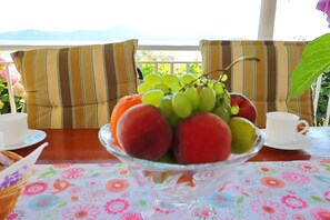 Ein Tisch mit einer Obstschale, zwei Tassen und gestreiften Kissen.