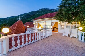 Ein Hotel mit rotem Ziegeldach, weißer Balkonbrüstung und Blick auf einen Berg.