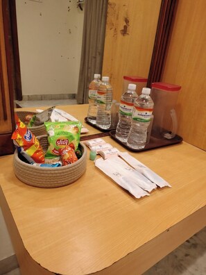 A hotel reception area with a wooden desk, a woven basket with snacks, bottled water, and a tissue box.