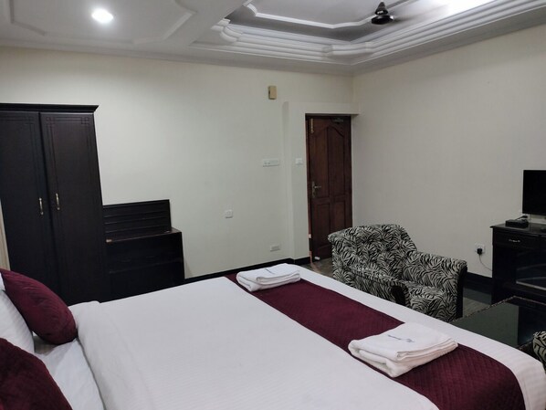 A hotel room with a bed, a chair, a wardrobe, and a television.