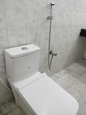 A bathroom with a toilet, a shower, and a sink.
