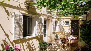 A sunlit courtyard with a table and chairs, a small plant, and a door. - Rooms Batina - Double Room-1 (Dubrovnik)