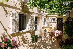 A sunlit courtyard with a table and chairs, a small plant, and a door. - Rooms Batina - Double Room-1 (Dubrovnik)