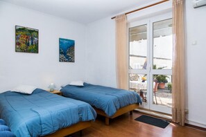 Ein Zimmer mit zwei Betten, einem Vorhangfenster und zwei Bildern an der Wand.