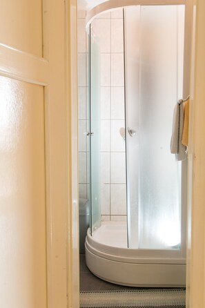 Eine gläserne Duschkabine mit weißer Tür und einem Handtuchhalter an der Wand.