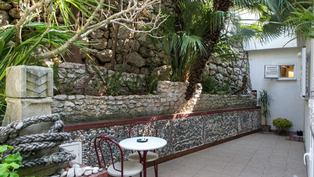 An outdoor patio with a stone wall, a small table, and two chairs. - Plavi Zal Apartment - One Bedroom Apartment With Two Terraces (Dubrovnik)