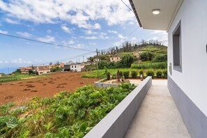 Ein Balkon mit Blick auf einen Garten und Häuser im Hintergrund.