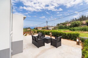 Eine Außenpatio mit Tisch und Stühlen, einem Kiesweg und Blick auf Häuser und Grünflächen im Hintergrund.