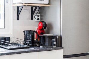 Eine Küche mit einer Kaffeemaschine, einem Toaster und einem Wasserkocher auf der Arbeitsfläche.