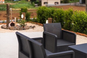 Korbmöbel im Freien mit Blick auf einen angelegten Garten.