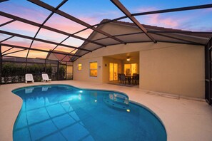 An indoor swimming pool with a glass ceiling, surrounded by a patio area with chairs and a table. - Screened Pool | Lanai Dining + Grill | One-Level | Near Parks | Palm & Preserve (Davenport)