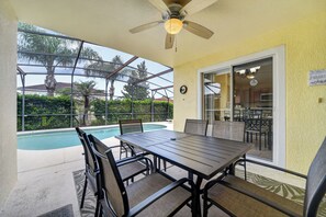 Eine Außenpatio mit Pool, Tisch und Stühlen sowie einem Deckenventilator.