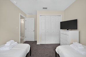Une chambre d’hôtel avec deux lits, une télévision, une armoire et une porte donnant sur une autre pièce.
