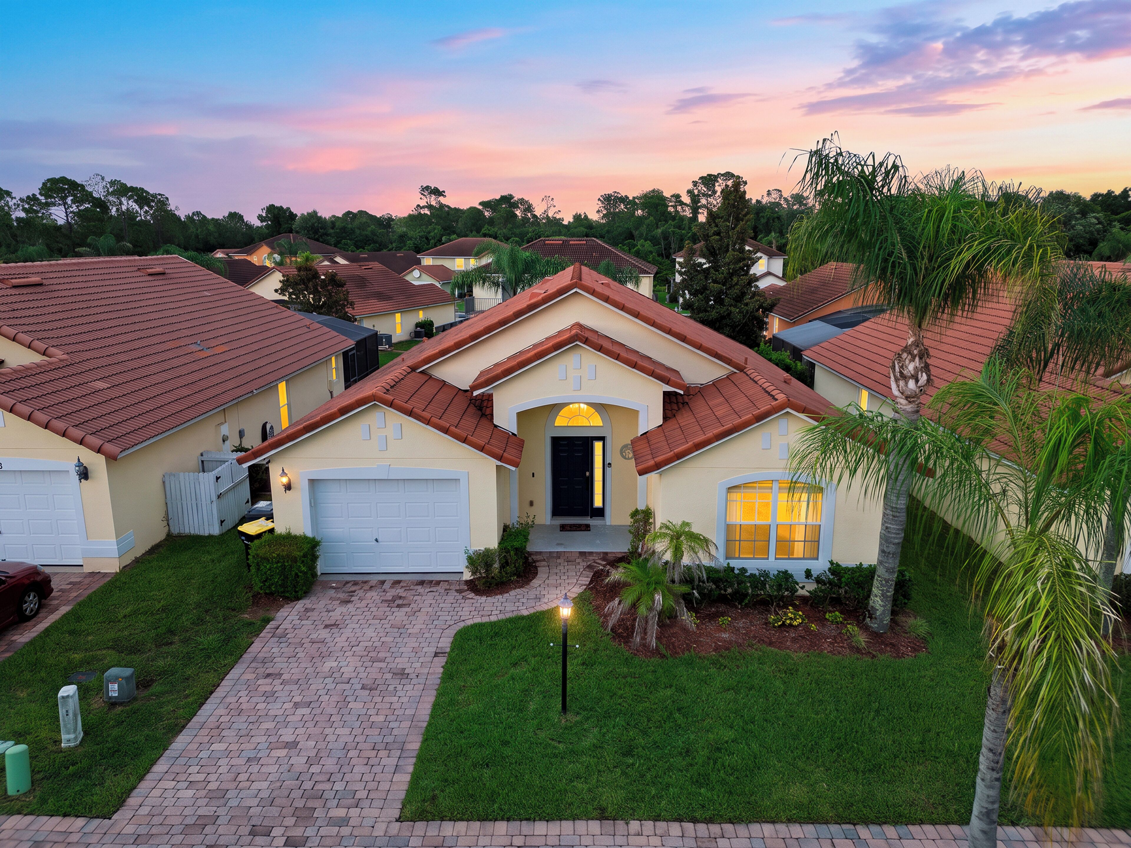 A residential area with multiple houses, a paved driveway, and a well-maintained lawn.