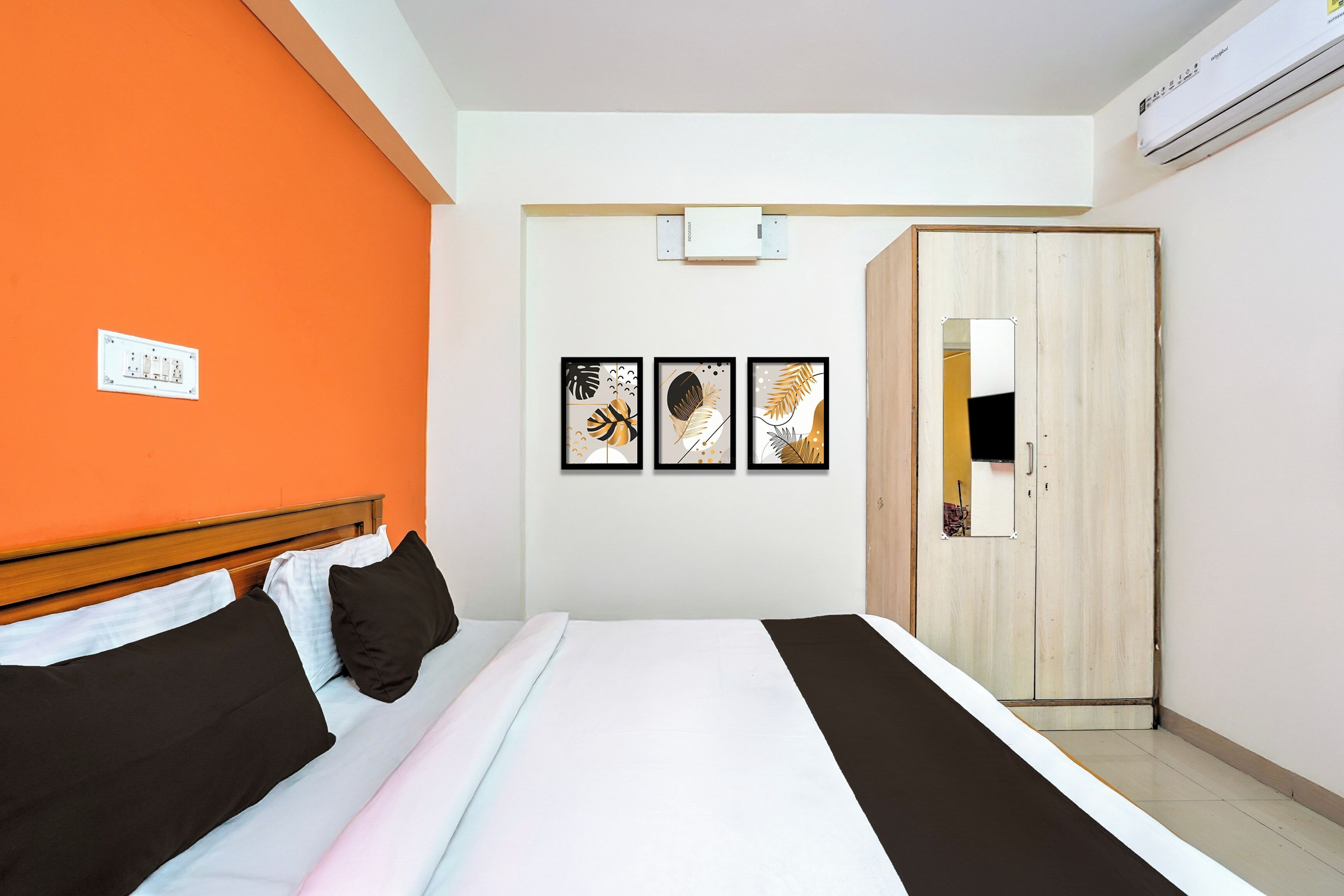 Una habitación de hotel con cama, armario y tres cuadros en la pared.