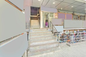 Una escalera conduce a una zona comercial con barandillas de metal y diversos artículos en exhibición.
