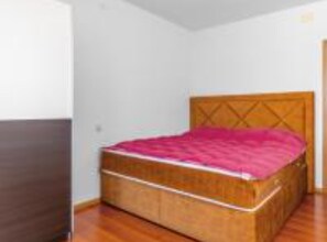 A single bed with a wooden headboard in a room with white walls and wooden flooring. - Three Bedroom Apartment With Balcony and Sea View (Crikvenica)