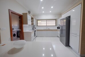 Uma cozinha moderna com ilha central, eletrodomésticos embutidos e janela com persianas.