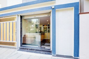 A hotel entrance with a glass door, a wooden door, and a blue and white exterior. - Collection O Kadugodi Tree Park (Bengaluru)