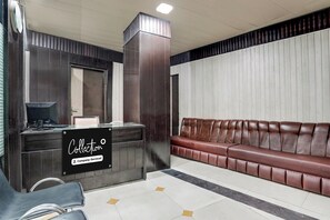 A reception area with a counter, a sign indicating company-serviced, a brown leather sofa, and a tiled floor. - Collection O Haridwar Railway Station (Haridwar)