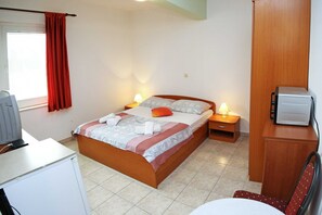 Ein Schlafzimmer mit Bett, Nachttischlampen, einem Schreibtisch mit Computer und einem Kleiderschrank.