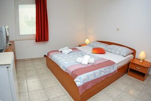 Ein ordentlich bezogenes Bett mit einem gemusterten Überwurf, zwei Kissen und einer Nachttischlampe.