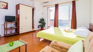 Una habitación con cama, televisión en un mueble, armario y balcón con vistas.