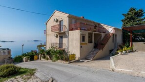 Ein zweistöckiges Gebäude mit einem Balkon, einer Treppe und Blick auf das Meer.