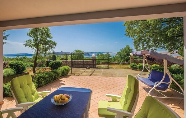 Eine Terrasse im Freien mit Esstisch, Stühlen und Blick auf das Meer.