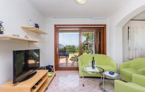 Ein Wohnzimmer mit Flachbildfernseher, einem Glastisch und einem grünen Sofa.