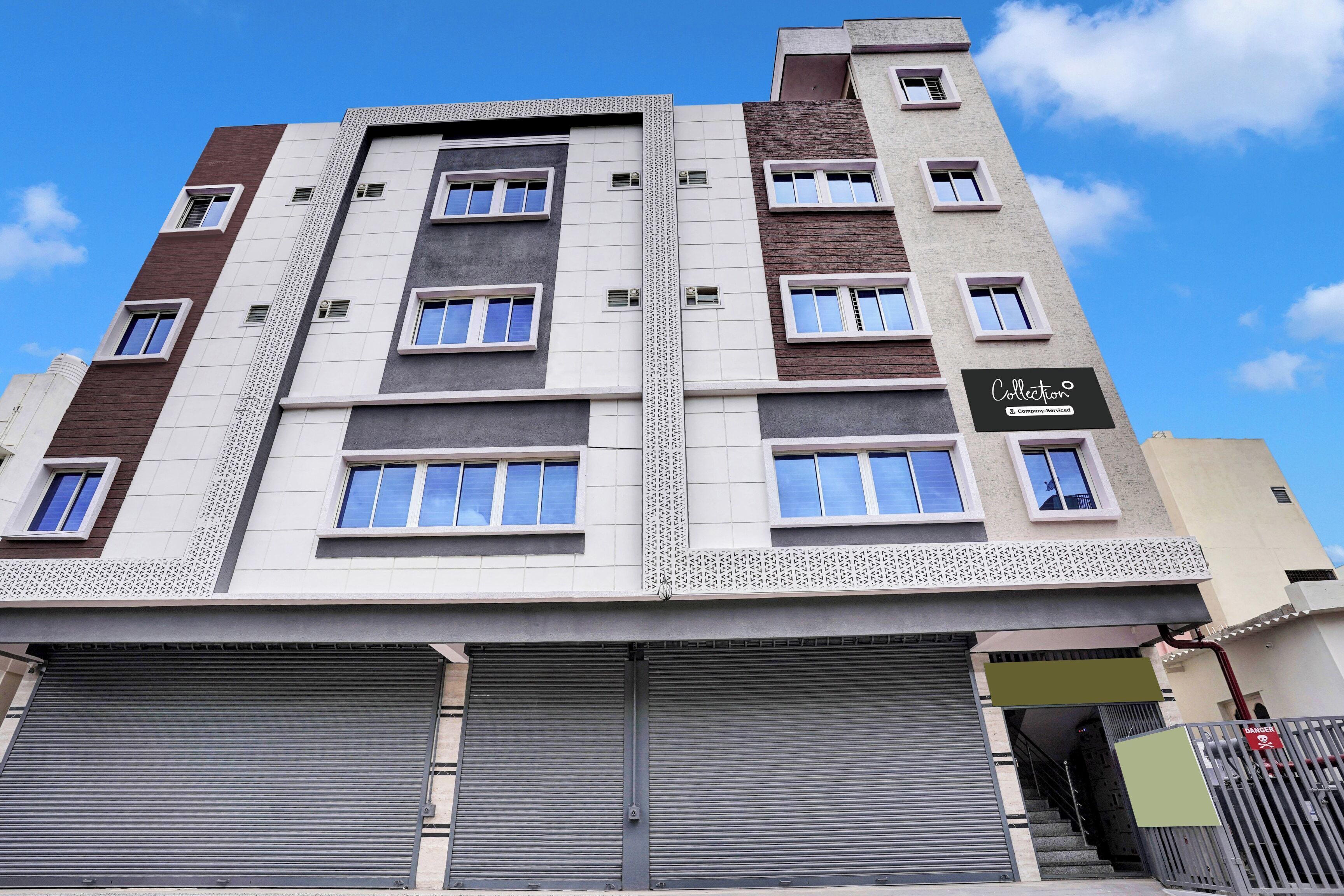 Un edificio de varios pisos con un diseño arquitectónico moderno, que presenta una combinación de fachadas de ladrillo y enlucido, ventanas grandes y un letrero de empresa.